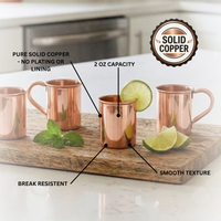 Four copper mini Moscow mule cups arranged on a wooden board with lime slices and mint, overlaid with callout labels describing the product features, plus a circular 'Solid Copper' badge.