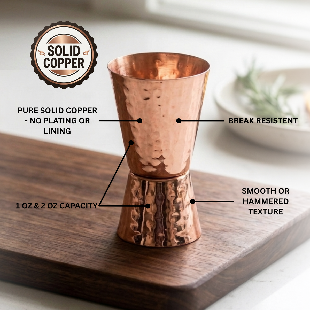 A copper jigger with hammered detail, shown on a wooden board with callout labels and a 'Solid Copper' badge. 