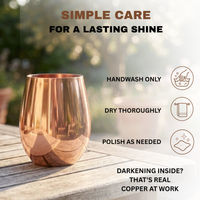 A copper wine cup sits on a wooden table outdoors with care instructions including 'HANDWASH ONLY,' 'DRY THOROUGHLY,' and 'POLISH AS NEEDED.