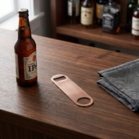 copper plated bottle opener next to a beer bottle on a wooden bar