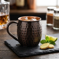 A hammered copper mug with a dark finish filled with iced set on a dark slate coaster. 